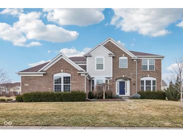 Beautiful two-story brick home featuring manicured landscaping and a charming blue front door at 13750 Hiatt Dr, Carmel, IN 46074