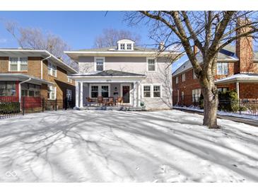 Charming two-story home with inviting front porch and snowy front yard, perfect for a Gathering at 4805 N Park Ave, Indianapolis, IN 46205
