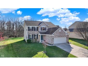 Charming two-story home featuring a brick facade and well-maintained lawn with mature trees against a blue sky at 5147 Nicodemus Dr, Plainfield, IN 46168