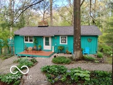 Charming turquoise home with a cozy front porch, surrounded by lush greenery and a stone pathway at 7166 N Oak Ridge Rd, Morgantown, IN 46160