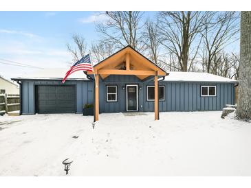 Charming single story home with covered porch, attached garage, and American flag in a snow covered yard at 150 W Jo Jo Ln, Nineveh, IN 46164