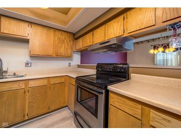 Traditional kitchen with wood cabinets, light countertops, and a black range at 4247 Larkspur Trce, Indianapolis, IN 46237