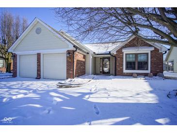 Charming home featuring a two-car garage and brick accents, set against a snowy landscape at 10953 Mount Vernon N Trl, Indianapolis, IN 46229