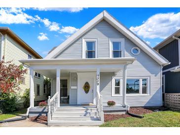 Charming two-story home featuring light gray siding, a welcoming front porch, and a well-maintained yard at 1339 S East St, Indianapolis, IN 46225