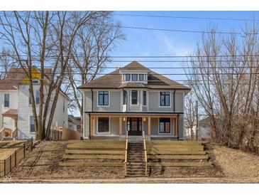 Beautiful two-story home with inviting front porch, landscaped stairs, and neutral siding against a blue sky at 2828 N Illinois St, Indianapolis, IN 46208