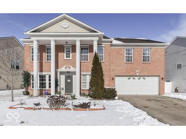 Charming two-story red brick home with large columns, an attached garage, and snow-covered front yard at 387 Legacy Blvd, Greenwood, IN 46143
