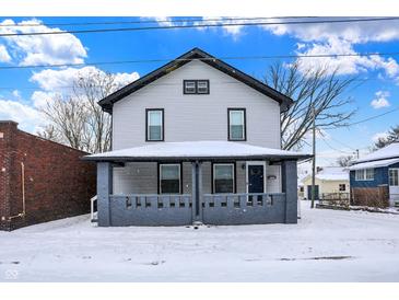 Charming two-story home with a covered front porch and snowy yard at 5053 E Michigan St, Indianapolis, IN 46201