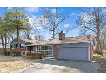 Charming single-Gathering home showcasing its brick and gray exterior with an attached garage and landscaped yard at 5124 Wexford Rd, Indianapolis, IN 46226