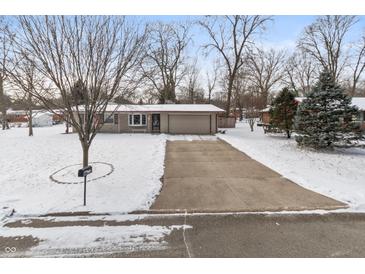 Charming ranch-style home featuring a spacious driveway and well-maintained front yard covered in a blanket of fresh snow at 6907 Buick Dr, Indianapolis, IN 46214