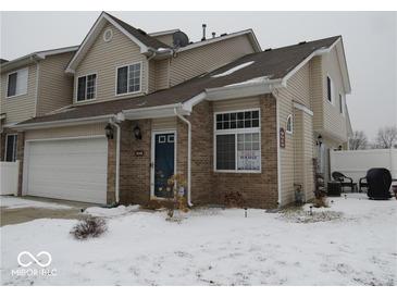 Two-story townhouse features a brick facade, attached garage, and snow-covered front yard at 8148 Shores Edge Way, Indianapolis, IN 46237