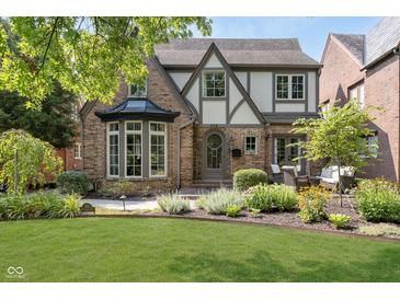Charming two-story home with a well-manicured lawn and beautiful landscaping at 219 Buckingham Dr, Indianapolis, IN 46208