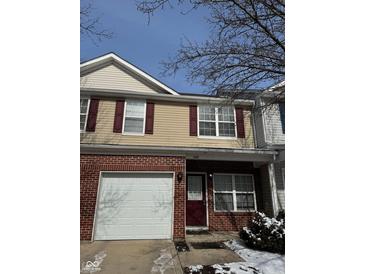 Charming two-story townhome featuring a brick facade, garage, and well-maintained front yard at 5142 Tuscany Ln, Indianapolis, IN 46254