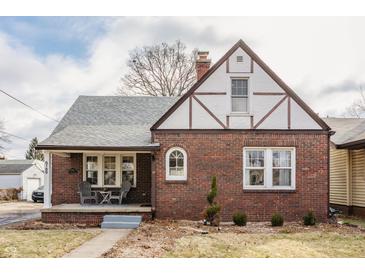 Charming brick Tudor-style home with a covered front porch and manicured landscaping at 6189 Primrose Ave, Indianapolis, IN 46220