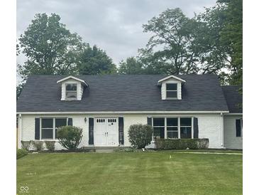 Charming white brick home featuring dormer windows, black shutters, and a lush green lawn at 8888 Cholla Rd, Indianapolis, IN 46240