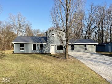 Charming single-story home with a metal roof, gray siding, a gravel driveway, and a well-manicured lawn at 6205 Beech Grove Rd, Martinsville, IN 46151