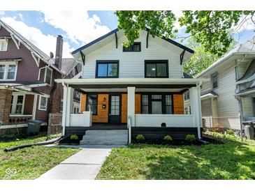 Charming two-story home with front porch featuring wood and white painted brick accents and manicured landscaping at 633 E 32Nd St, Indianapolis, IN 46205