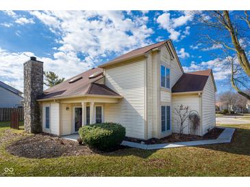 Charming home showcasing a stone chimney and vinyl siding with a neatly maintained front yard and blue skies at 6348 Bay Vista E Dr, Indianapolis, IN 46250