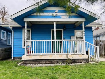 Charming blue one-story home featuring a covered front porch, complemented by a small front yard at 945 N Ewing St, Indianapolis, IN 46201
