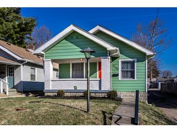 A quaint green house with an orange door, set against a bright blue sky at 1130 E Bradbury Ave, Indianapolis, IN 46203