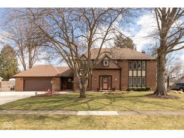 Charming brick home featuring a well-manicured lawn and a large mature tree in the front yard at 12107 Castle Row Overlook, Carmel, IN 46033