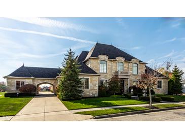 Stunning stone-clad home featuring a porte-cochere, manicured lawn, and beautiful mature trees at 1813 Milford St, Carmel, IN 46032