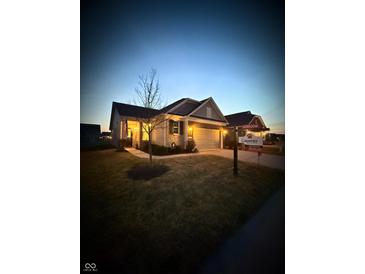 Charming single-story home with a two-car garage, landscaped front yard, and warm exterior lighting at twilight at 5003 Lilium Dr, Plainfield, IN 46168