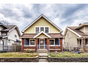 Charming two-story home with yellow and blue siding, brick accents, and a well-maintained front yard at 85 N Dearborn St, Indianapolis, IN 46201