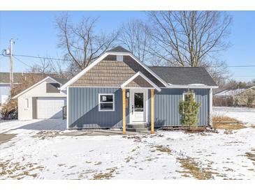 Charming home featuring blue siding and a covered porch with wood supports, complemented by a detached garage at 10539 Mcpherson St, Carmel, IN 46280