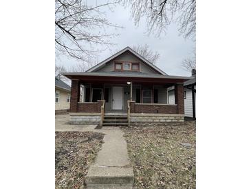 Charming home with brick-accented porch and stone foundation, offering classic curb appeal at 1207 N Kealing Ave, Indianapolis, IN 46201