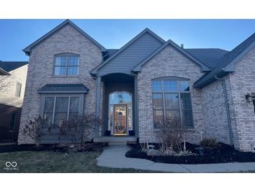 Charming brick home featuring a covered front entry, large windows, and professional landscaping at 13522 Spring Farms Dr, Carmel, IN 46032