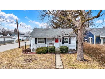 Charming home with tidy landscaping, front porch, and red front door at 2002 Fisher Ave, Indianapolis, IN 46224