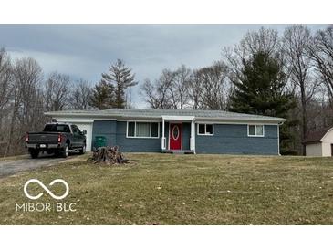 Charming one-story home with a gray facade, a red door, mature trees, and a well-manicured lawn at , Monrovia, IN 46157