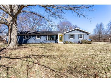 Charming blue single-story home with a sunny yellow front door and a well-manicured front yard at 320 E 86Th St, Indianapolis, IN 46240