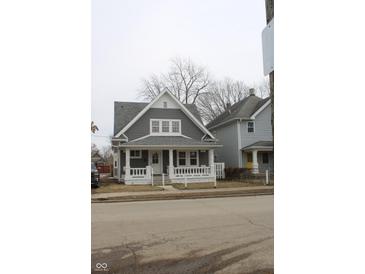 Attractive gray home featuring a covered porch with decorative columns and a well-maintained lawn at 21 S Warman Ave, Indianapolis, IN 46222