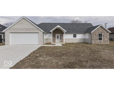 Charming single-story home featuring a brick and stone facade, attached garage, and well-manicured lawn at 32 Downing Dr, Trafalgar, IN 46181