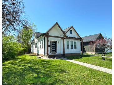 Charming two-story home with a modern door and a well-manicured lawn under a clear blue sky at 1818 N Cornell Ave, Indianapolis, IN 46202