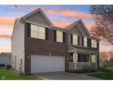 Two-story brick home featuring a two-car garage and inviting front porch at 10887 Gresham Pl, Noblesville, IN 46060