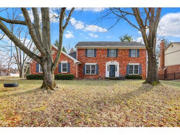 Charming two-story red brick home with blue shutters surrounded by mature trees and a green front lawn at 4783 Briarwood Trce, Carmel, IN 46033