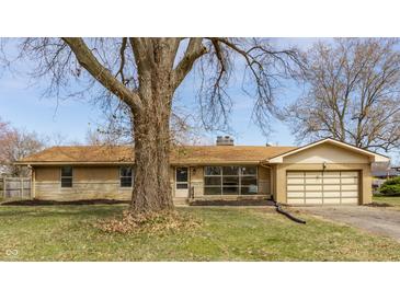 Charming single-story home with a tan brick exterior, attached garage, and mature landscaping at 5210 Ashbourne Ln, Indianapolis, IN 46226
