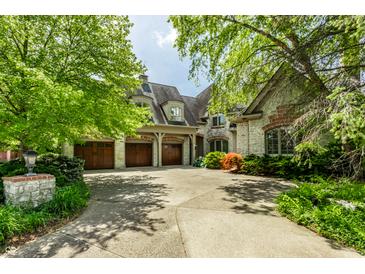 View of a home's three-car garage and stone brick facade and manicured front yard at 6560 Dawson Lake Dr, Indianapolis, IN 46220