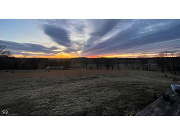 Scenic view of a vibrant sunset over a grassy field with trees in the distance at 1125 S Buffalo Hill Rd, Martinsville, IN 46151