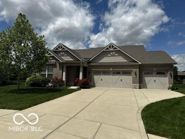 Charming brick home featuring an attached three-car garage, well-manicured lawn, and beautiful landscaping at 6117 Arctic Cir, Indianapolis, IN 46237
