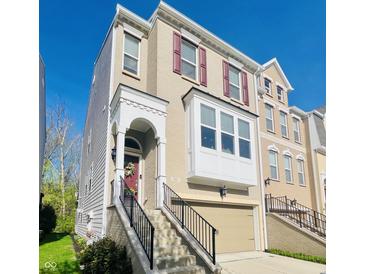 Charming townhome featuring a red front door, attached garage, and a combination of siding and brick at 700 Greenford N Trl, Carmel, IN 46032