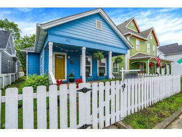 Charming blue home featuring a white picket fence, cozy front porch, and well-maintained landscaping at 912 Harlan St, Indianapolis, IN 46203