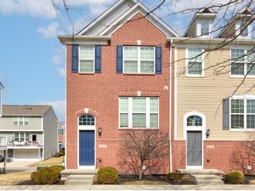Brick townhome featuring blue shutters, a blue door, and manicured landscaping at 14041 Wimbleton Way, Fishers, IN 46037