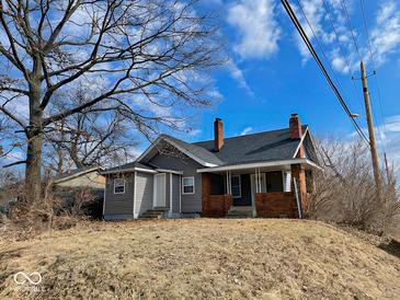 Two-story home features brick accents, a covered front porch, and a mature shade tree at 3132 E 36Th St, Indianapolis, IN 46218