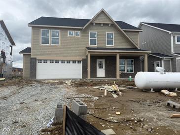 Two-story home features a white garage door, brick and tan shingle siding, and a covered porch for a welcoming facade at 7316 Broadview, McCordsville, IN 46055
