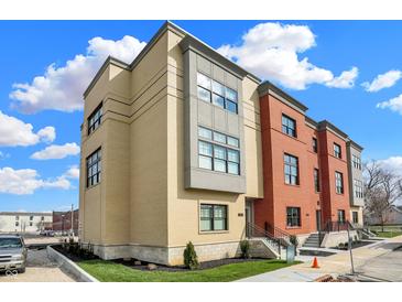 A modern condominium showcases a brick and tan facade, complemented by well-manicured landscaping and clear blue skies at 76 E Wayne St # B, Franklin, IN 46131