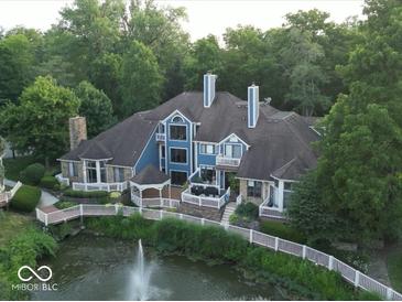 Stunning aerial view of a blue house with lush landscaping and a serene water feature at 8061 Lower Bay Ln # 1, Indianapolis, IN 46236