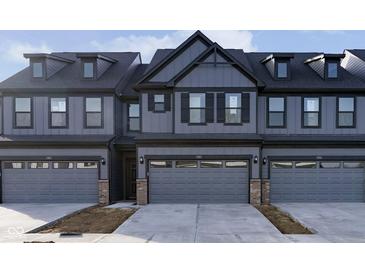 Gray townhome exterior featuring a three-car garage, dark trim, and modern design at 9730 Behner Dr, Fishers, IN 46250